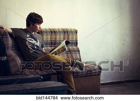Picture - Caucasian man reading in living room. Fotosearch