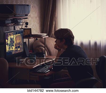 Stock Image - Caucasian man watching computer screen at desk. Fotosearch