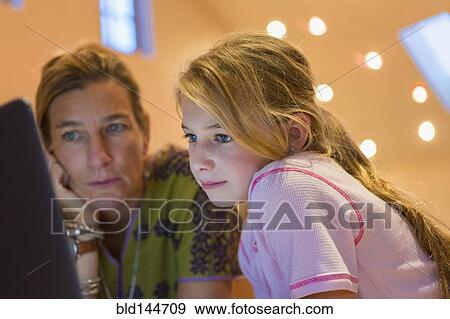 Stock Photo - Caucasian mother and daughter using computer together. Fotosearch