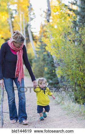 Stock Photo - Caucasian mother and son hiking on dirt path in forest. Fotosearch