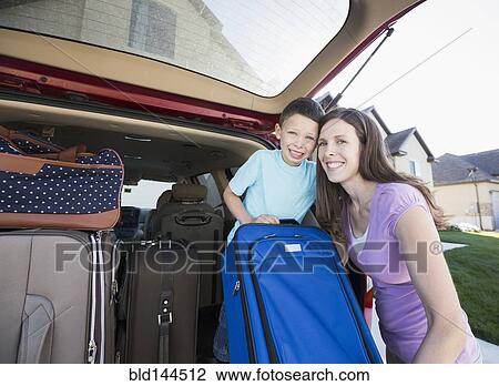 Stock Image - Caucasian mother and son smiling with suitcases in car. Fotosearch
