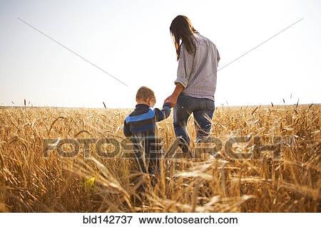 Stock Photo - Caucasian mother and son walking in rural field. Fotosearch