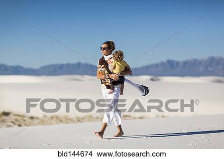 Caucasian mother carrying son on sand dune View Large Photo Image Picture - Caucasian mother carrying son on sand dune. Fotosearch