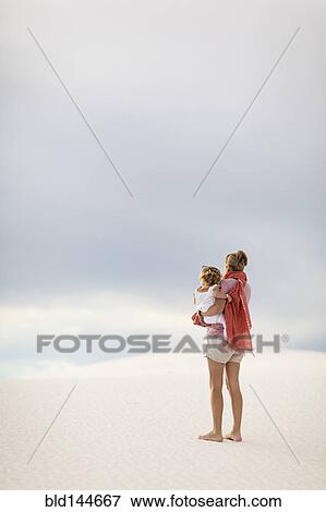 Caucasian mother holding son on sand dune View Large Photo Image Stock Photo - Caucasian mother holding son on sand dune. Fotosearch