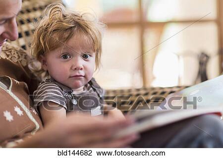 Stock Image - Caucasian mother reading to son in chair. Fotosearch