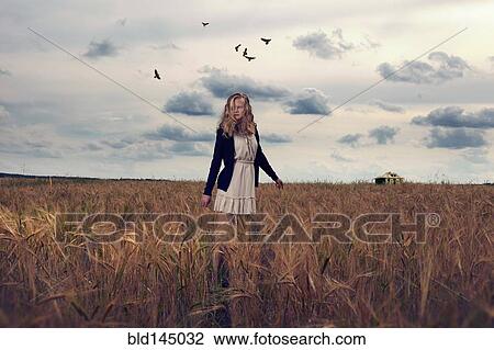 Stock Image - Caucasian teenage girl standing in field of tall grass. Fotosearch