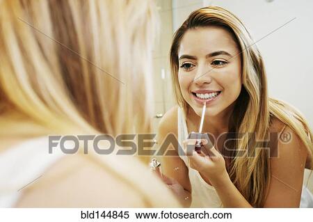 Stock Photography - Caucasian woman applying makeup in bathroom mirror. Fotosearch