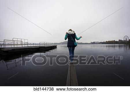 Caucasian woman balancing on dock over still lake View Large Photo Image Stock Photo - Caucasian woman balancing on dock over still lake. Fotosearch