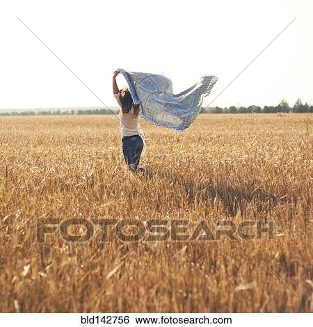 Stock Photograph - Caucasian woman carrying blanket in rural field. Fotosearch