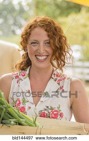 Stock Photo - Caucasian woman carrying crate of produce. Fotosearch