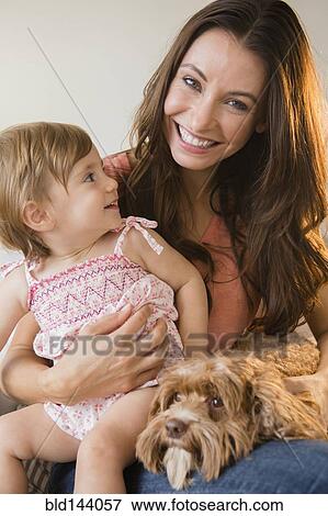Stock Photo - Caucasian woman holding daughter and pet dog. Fotosearch