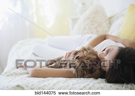Stock Photography - Caucasian woman hugging pet dog in bed. Fotosearch