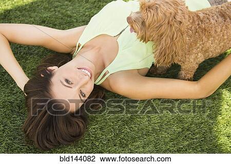 Stock Image - Caucasian woman playing with dog on lawn. Fotosearch
