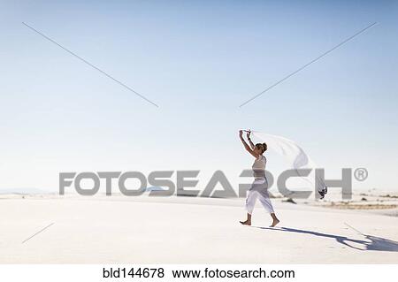 Caucasian woman playing with scarf on sand dune View Large Photo Image Stock Photo - Caucasian woman playing with scarf on sand dune. Fotosearch