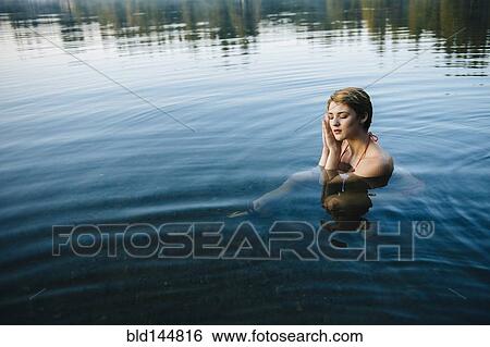 Stock Photograph - Caucasian woman sleeping in still lake. Fotosearch