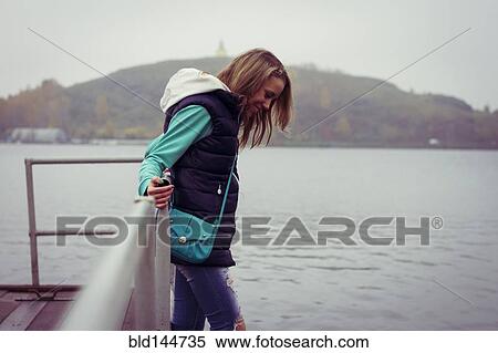 Stock Photography - Caucasian woman standing on dock over still lake. Fotosearch