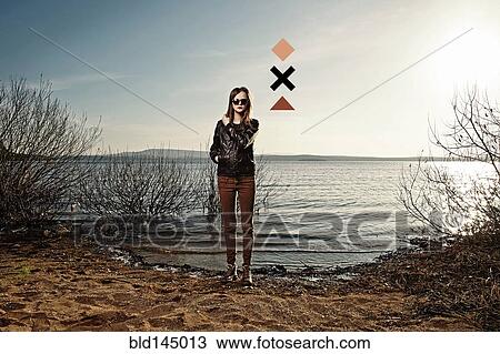 Stock Image - Caucasian woman standing on sandy beach. Fotosearch