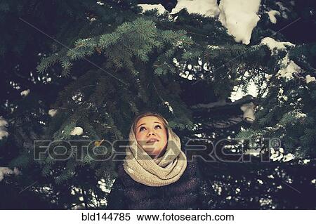 Stock Photography - Caucasian woman standing under evergreen tree branches. Fotosearch