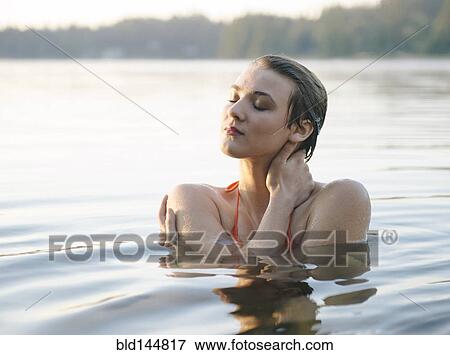 Stock Photo - Caucasian woman swimming in still lake. Fotosearch