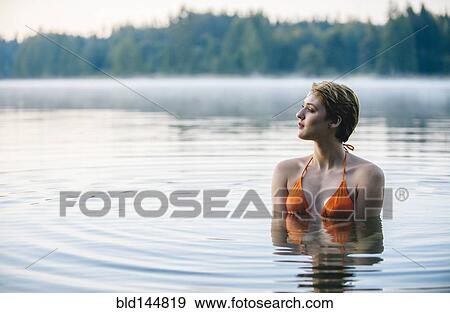 Stock Photo - Caucasian woman swimming in still lake. Fotosearch
