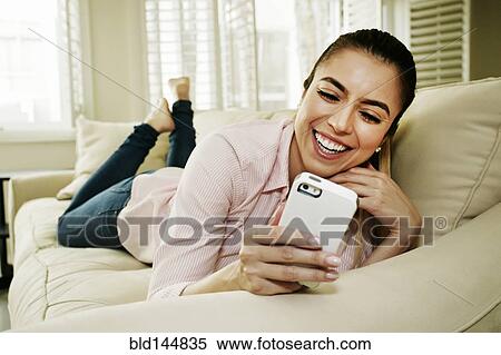 Caucasian woman using cell phone on sofa View Large Photo Image Stock Photography - Caucasian woman using cell phone on sofa. Fotosearch