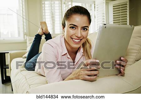 Caucasian woman using digital tablet on sofa View Large Photo Image Picture - Caucasian woman using digital tablet on sofa. Fotosearch