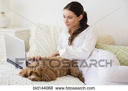 Stock Photo - Caucasian woman using laptop with pet dog. Fotosearch