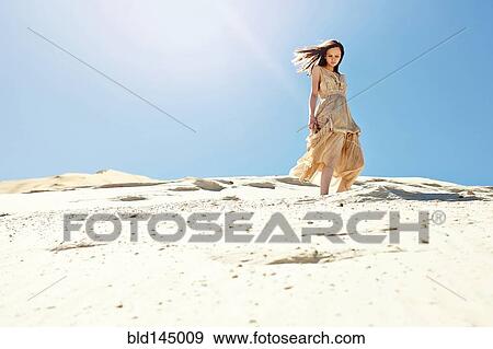Caucasian woman walking on sand dune hill View Large Photo Image Stock Photo - Caucasian woman walking on sand dune hill. Fotosearch