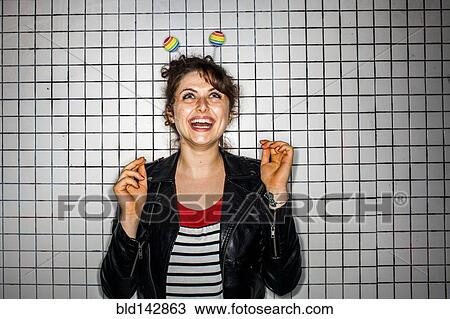 Stock Image - Caucasian woman wearing colorful antenna near wall. Fotosearch