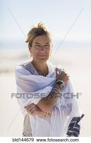 Stock Photo - Caucasian woman wrapped in scarf on sand dune. Fotosearch