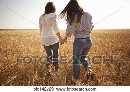 Caucasian women holding hands in rural field View Large Photo Image Stock Photo - Caucasian women holding hands in rural field. Fotosearch