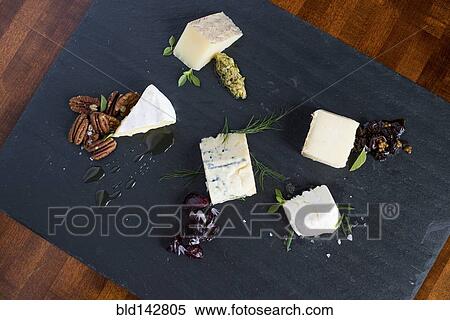Stock Photography - Cheese and herbs on cutting board. Fotosearch