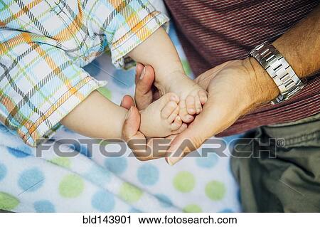 Close up of Caucasian father holding feet of baby boy View Large Photo Image Stock Image - Close up of Caucasian father holding feet of baby boy. Fotosearch