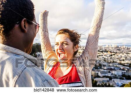 Stock Photo - Couple cheering near scenic view of cityscape. Fotosearch
