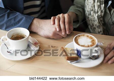 Stock Image - Couple holding hands in cafe. Fotosearch