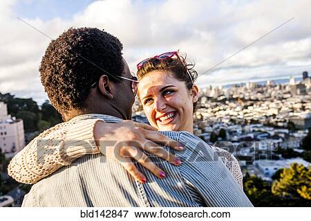 Stock Photo - Couple hugging near scenic view of cityscape. Fotosearch