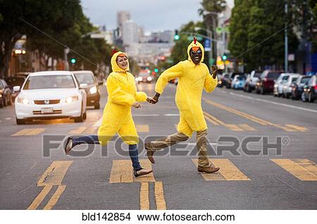 Picture - Couple in chicken costumes crossing city street. Fotosearch