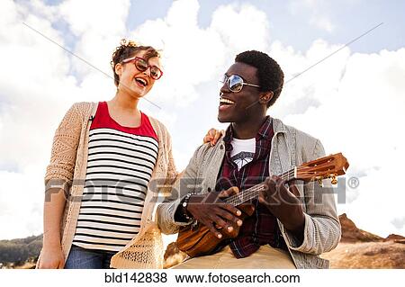 Stock Photo - Couple singing together and playing ukulele outdoors. Fotosearch