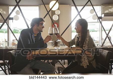 Stock Image - Couple toasting with wine in cafe. Fotosearch
