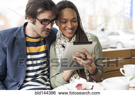 Stock Photograph - Couple using digital tablet in cafe. Fotosearch
