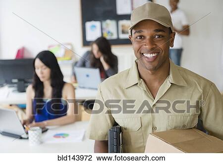 Stock Image - Delivery man smiling in office. Fotosearch