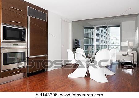 Stock Photograph - Dining table, oven and cabinets in modern kitchen. Fotosearch