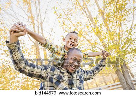 Stock Photo - Father carrying son outdoors. Fotosearch