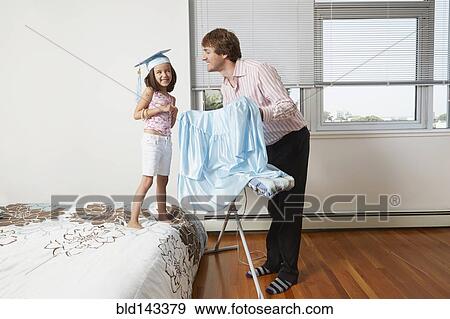 Stock Photo - Father helping daughter with graduation robes. Fotosearch