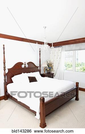 Stock Photograph - Four-poster bed and window in ornate bedroom. Fotosearch