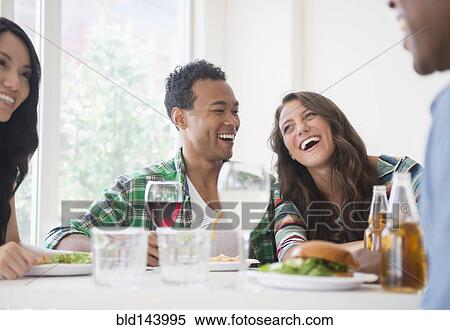Stock Photography - Friends laughing together at restaurant. Fotosearch