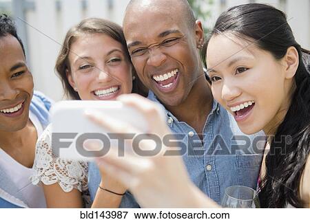 Stock Photo - Friends taking cell phone photograph at party. Fotosearch