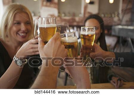 Stock Photograph - Friends toasting with beer in cafe. Fotosearch