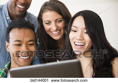 Stock Image - Friends using digital tablet together. Fotosearch