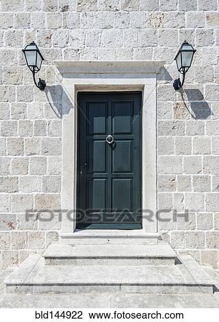 Stock Image - Front door and lamps of stone building. Fotosearch
